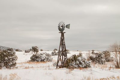 American-style windmill on snow covered field against sky