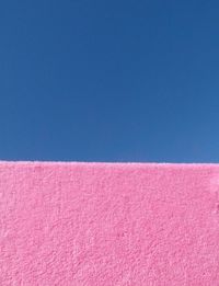 Low angle view of pink wall against clear blue sky