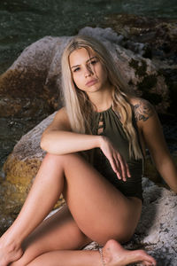 Beautiful young woman sitting on rock