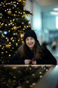 Portrait of a smiling young woman with christmas tree