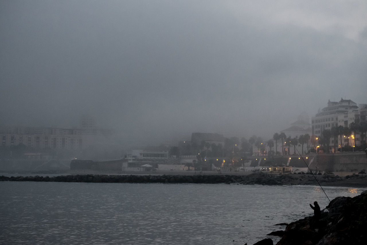 BUILDINGS BY SEA AGAINST SKY IN CITY