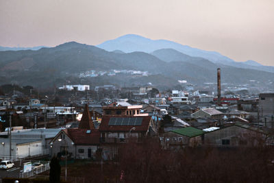 Scenic view of mountain range by town against clear sky at dawn