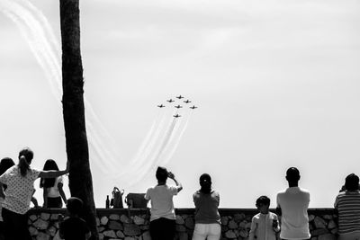 Rear view of people standing against sky