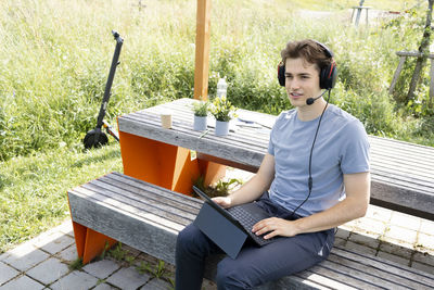 Young woman using laptop while sitting on bench