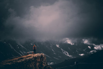 Person standing on mountain against sky