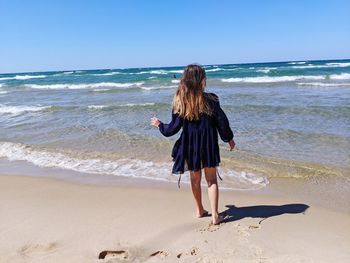 Rear view of woman on beach against sky