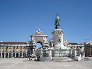 Low angle view of statue at praca do comercio against clear blue sky