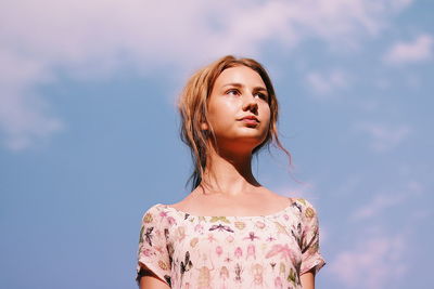 Portrait of a beautiful young woman standing against sky