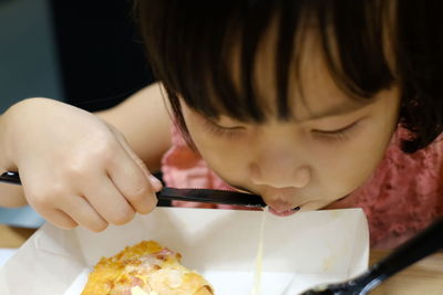 Close-up portrait of girl eating pizza 