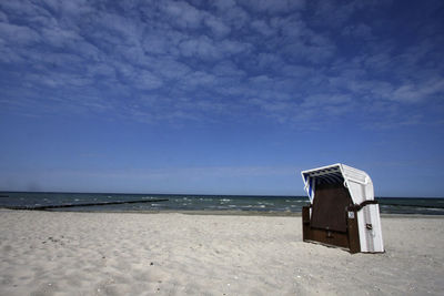 Hooded beach chair at shore against sky