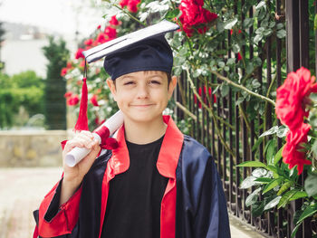 Portrait of woman wearing graduation gown standing in traditional clothing