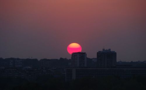 Silhouette buildings against clear sky at sunset
