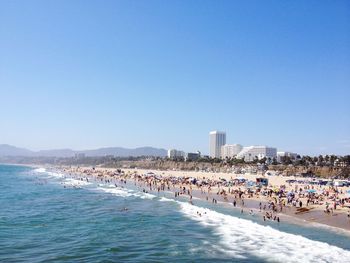 Crowd at beach against clear blue sky