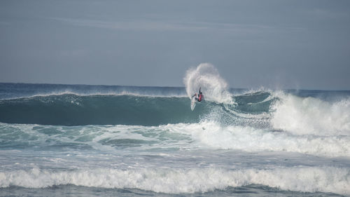 Surfer in sea against sky