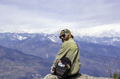 Traveler sitting on rock and enjoying snowy mountain view