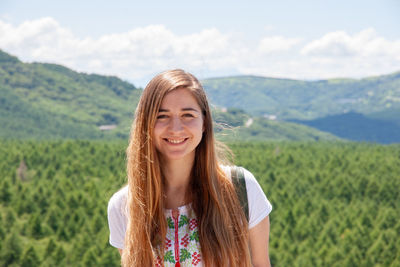 Portrait of smiling young woman against mountains