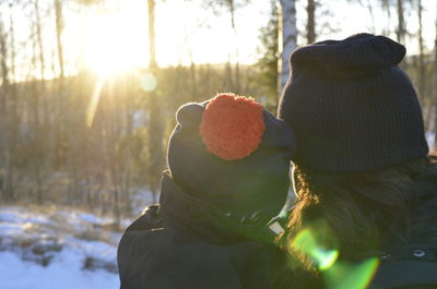 Rear view of mother and child against trees during winter