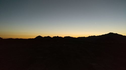 Scenic view of silhouette mountains against clear sky at sunset