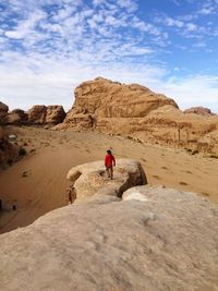 Man walking on rock against sky