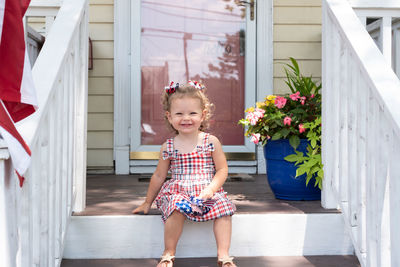 Full length portrait of smiling girl standing against building