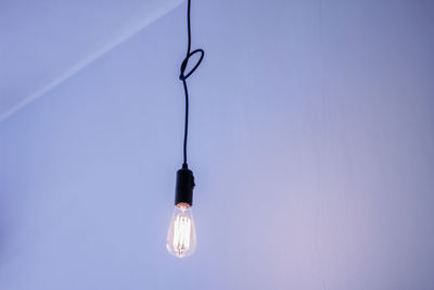 Low angle view of light bulb hanging against wall