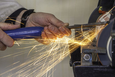 Cropped hand of man grinding metal in factory 