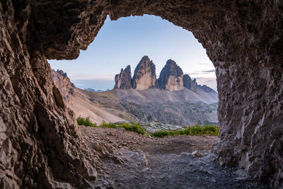 Rock mountain seen through cave against sky
