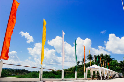 Low angle view of colorful fabrics waving against sky at beach