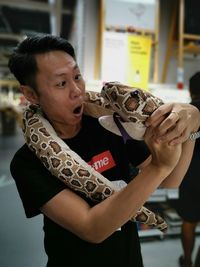 Shocked mature man holding toy snake while standing on floor