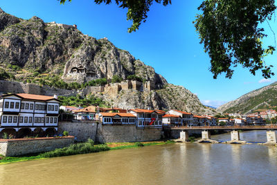 Houses by river and mountains against sky