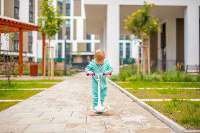 Girl standing on footpath by building