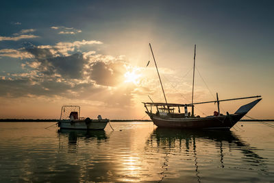 Fishing boats in sea against sky during sunset