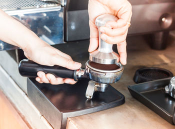 Cropped hands crushing coffee beans with equipment