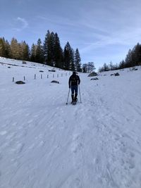 Rear view of person on snow covered field against sky