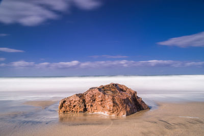 Rock formation on beach against sky