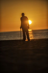 Full length of silhouette man standing on shore at beach during sunset