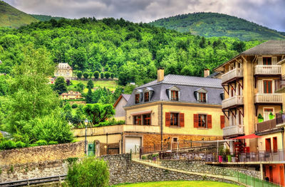 Houses by trees and buildings against sky