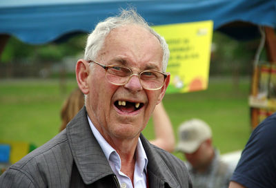 Portrait of gaped tooth senior man smiling while standing at park