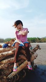 Full length of woman sitting on land against sky