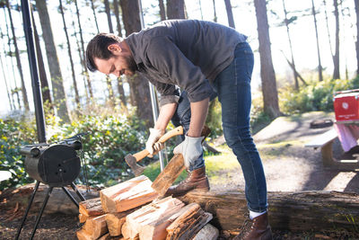 Full length of man cutting logs in forest