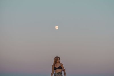 Rear view of woman standing against clear sky with full moon