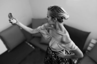 High angle view of woman holding hand mirror while standing at home