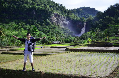 Full length of man standing by waterfall