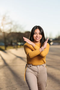 Portrait of young woman standing against sky