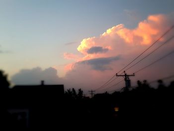 Low angle view of electricity pylon at sunset