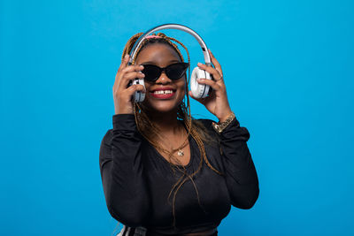 Young woman wearing sunglasses against blue background