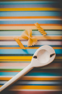 Raw pasta and wooden spoon on table