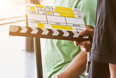 Midsection of man holding film slate while standing outdoors