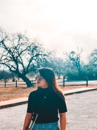 Young woman standing on road against sky