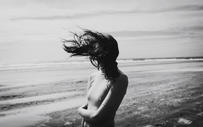 Woman standing on beach against sky